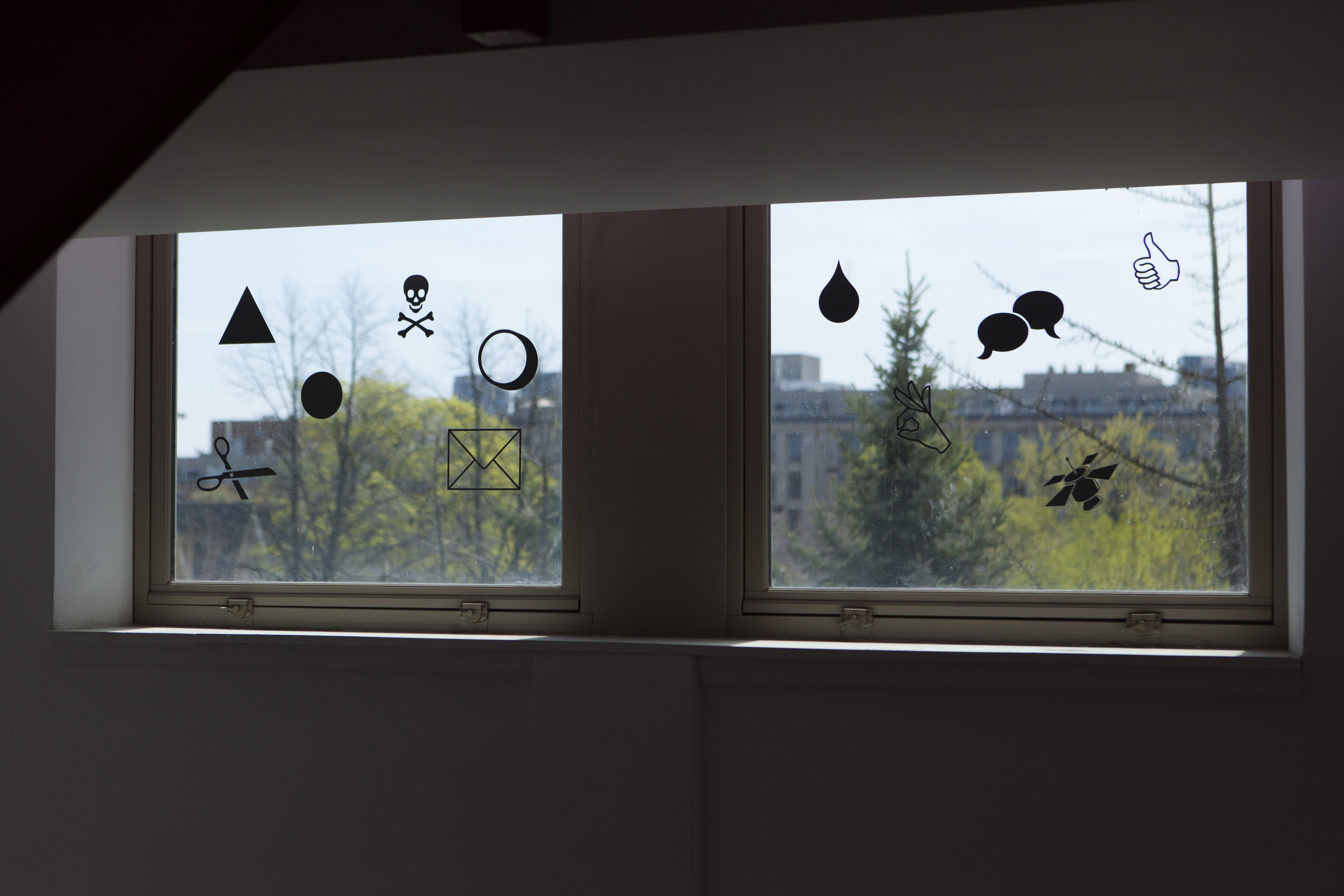 (Can) u c? am (eye) living n a HOLO U?, Maggie Groat and Jimmy Limit, 2017, site-specifc transparent images and opaque cut vinyl icons applied to windows at Artscape Youngplace, from Signals and Sentiments, Critical Distance Centre for Curators. Installation documentation by Josée Pedneault.