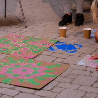Kolam patterns drawn on cardboard and on the brick floor.
