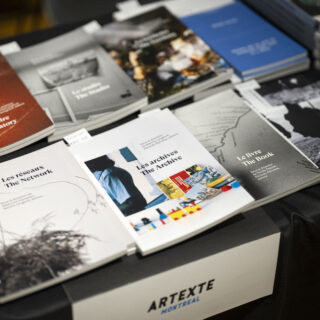 A black table with a white label reading Artexte is stacked with multiple softcover books.