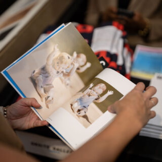 A light skinned person flips through a glossy, hardcover book.