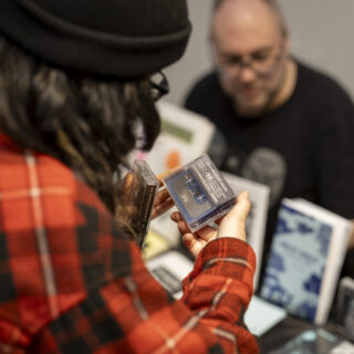 A person wearing a bright red flannel examines a tape record.