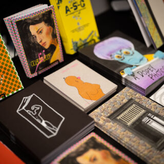 Various colourful, risograph printed zines and prints are displayed on a table with a black table cloth.