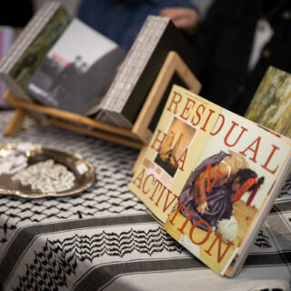 An open copy of PATINAPATINA Magazine's first issue is on display, showing a two page spread that reads "Residual Activation" on a table with a kuffiyeh.