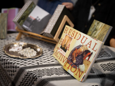 An open copy of PATINAPATINA Magazine's first issue is on display, showing a two page spread that reads "Residual Activation" on a table with a kuffiyeh.