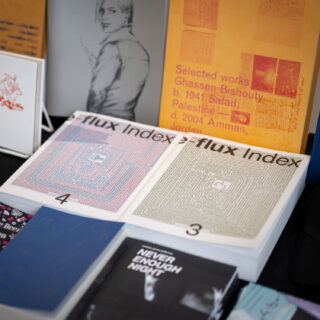 A black table-clothed table filled with books features titles including "e-flux index 4", "Never Enough Night" and "Selected works Ghassam Bishouty".