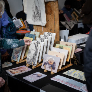 A table displays multiple illustration prints on bamboo racks.