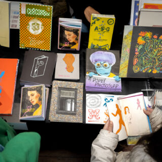 Various colourful, risograph printed zines and prints are displayed on a table with a black table cloth.