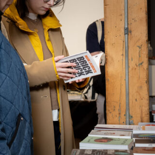 A light skinned woman wearing a yellow scarf looks through a book titled BRICK BRICK BRICK