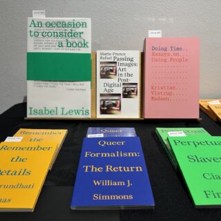 On a table with a black table cloth, multiple bright covered books are on display, titles include "Queer Formalism: The Return", "Remember the Details", and "Doing Time: Essays on Using People".