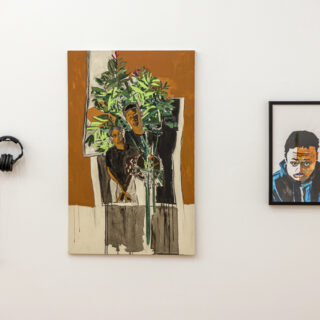 An art installation with a painting of two people standing with a plant in the centre, a framed portrait of a person in a blue sweater on the right, and a set of headphones with a QR code on the left.