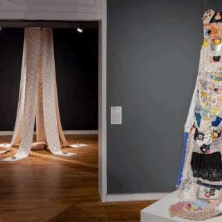 Installation view of two textile pieces. Left: cascading beige drapery under spotlights. Right: multi-fabric tapestry hung on a dark wall.