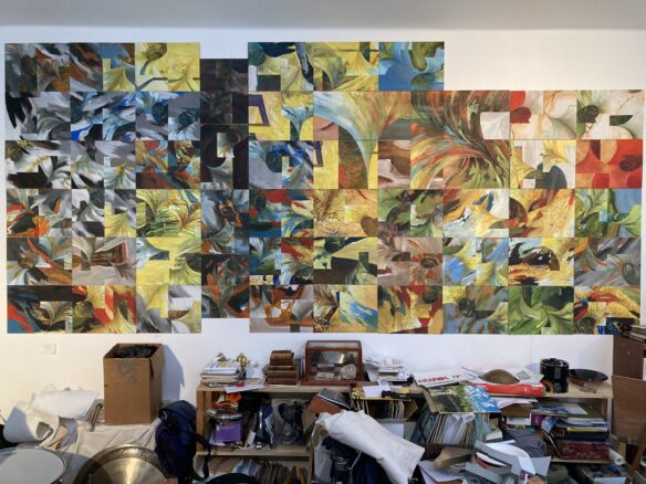 A large assemblage of colourful abstract paintings takes up an entire wall in an artist's cluttered studio