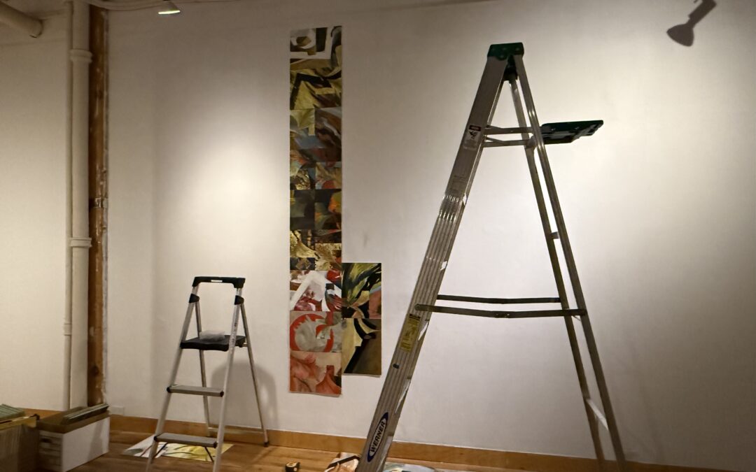 Abstract panel paintings are installed on a white wall, with a small ladder beside them and a larger ladder in front.