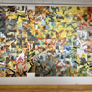 A large wall covered with many small abstract paintings arranged in a colourful grid.