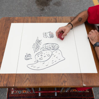 Image of an individual drawing on a white sheet of paper.